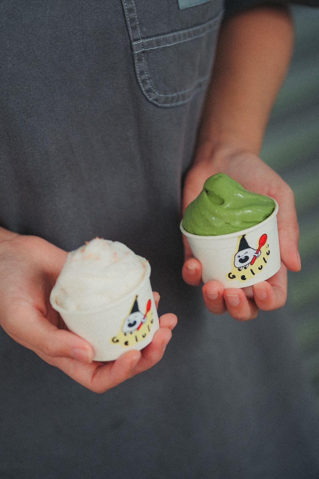 Two small cups of gelato held out