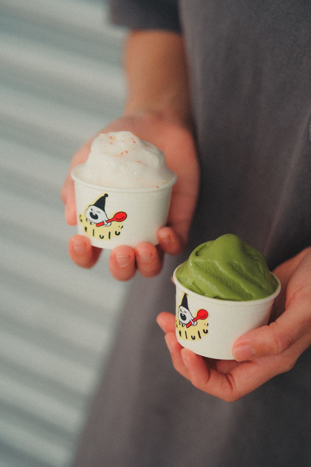 Two Gelulu cups held out, one pink, one matcha